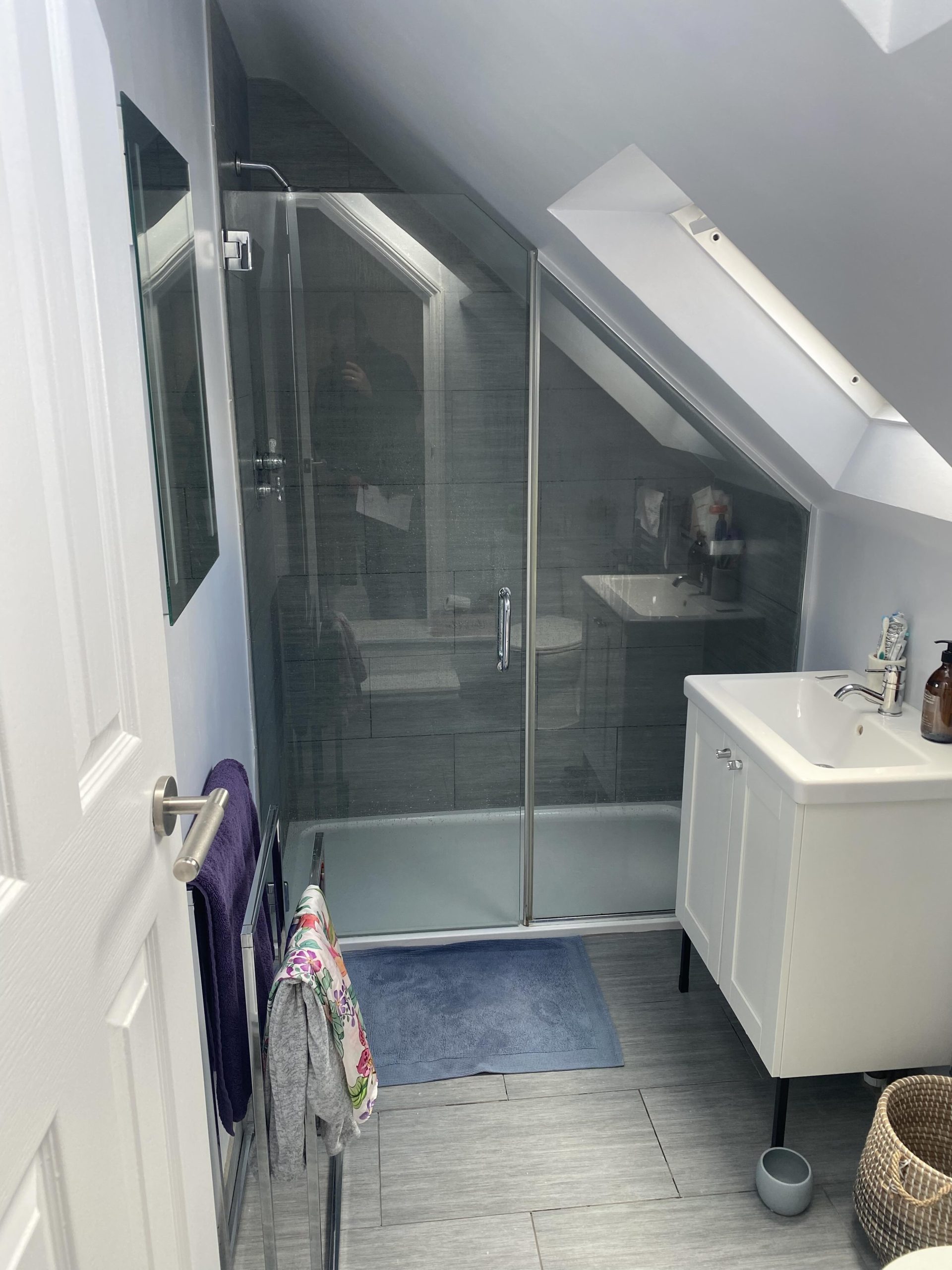 Existing loft bathroom before refurbishment with sloped ceiling, shower enclosure, and outdated layout ready for renovation.