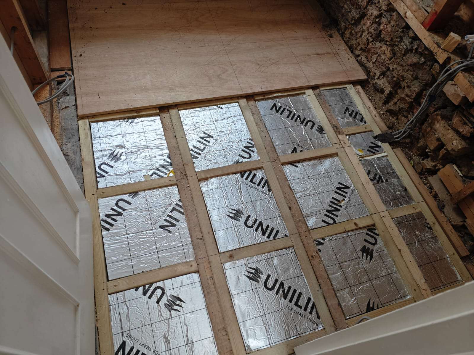 Bathroom floor preparation with insulated timber joists and structural subfloor before waterproofing and tiling.