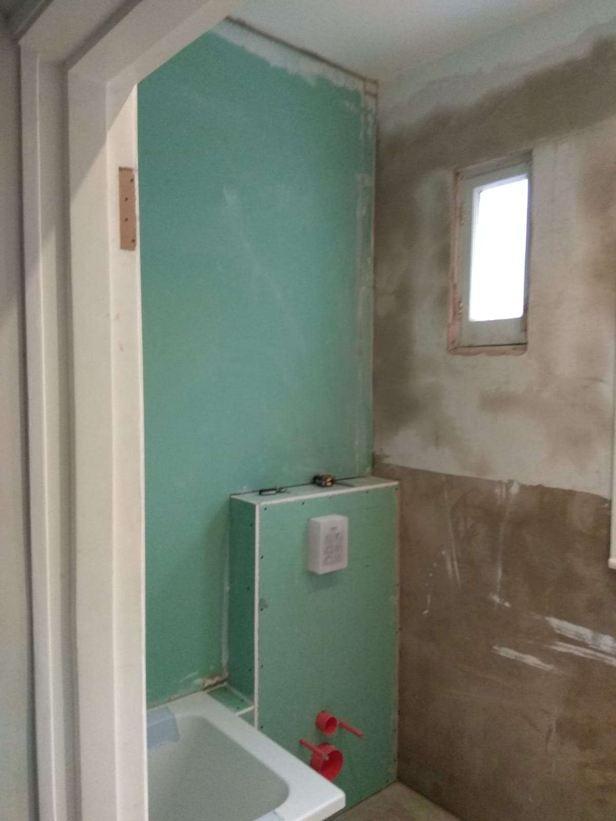 Bathroom under construction with moisture-resistant plasterboard, concealed cistern, and walls prepared before waterproofing and tiling.
