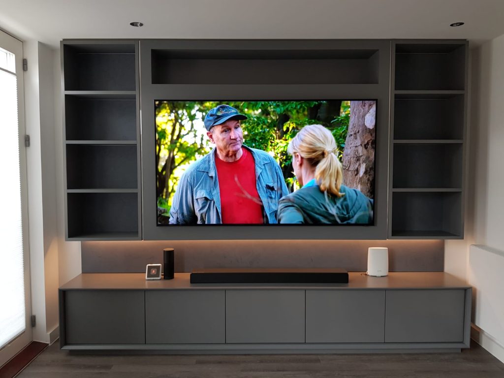 Bespoke fitted media wall with TV, shelving, storage cabinets and integrated lighting
